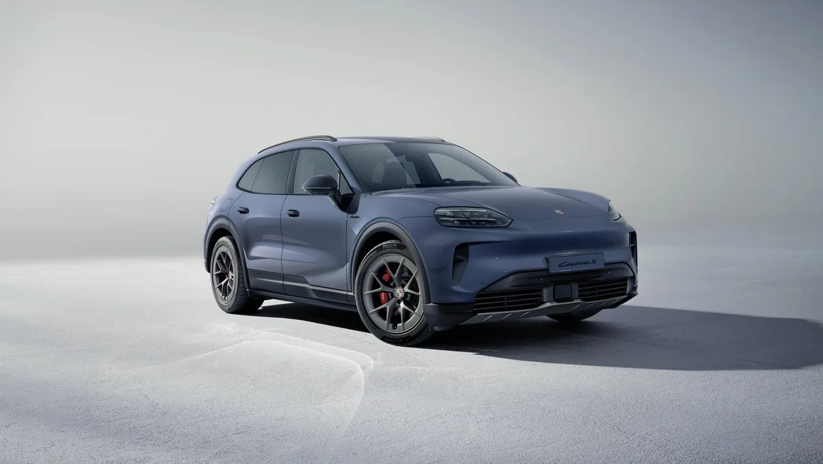 Modrošedý Cayenne S Electric ve studiu na světlém pozadí, zepředu zprava; černé prahy a lemy blatníků, červené brzdové třmeny.