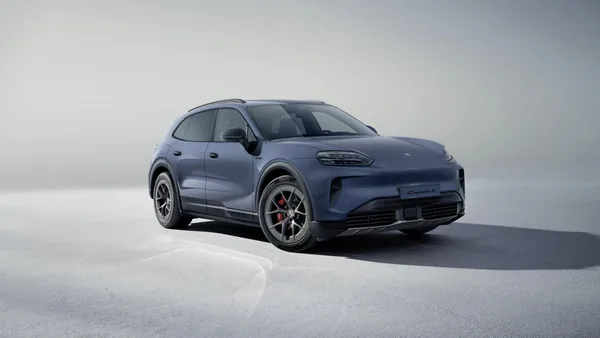 Modrošedý Cayenne S Electric ve studiu na světlém pozadí, zepředu zprava; černé prahy a lemy blatníků, červené brzdové třmeny.