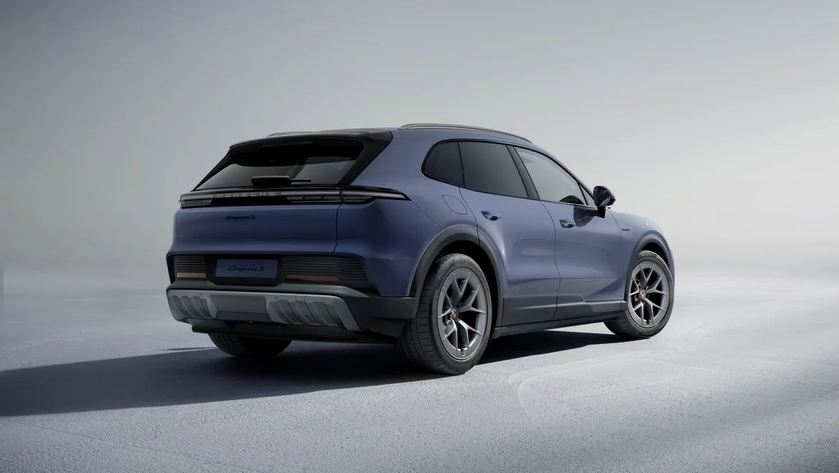 Modrošedý Cayenne S Electric ve studiu zezadu zleva; přes celou šířku spojité zadní světlo, pod ním černý difuzor.