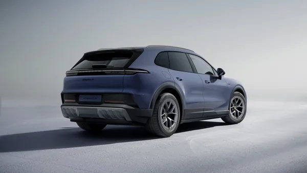 Modrošedý Cayenne S Electric ve studiu zezadu zleva; přes celou šířku spojité zadní světlo, pod ním černý difuzor.