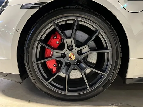 Detail kola: černý ráfek s paprsky do V, za ním červený brzdový třmen a kotouč, pneumatika s nápisem PIRELLI.