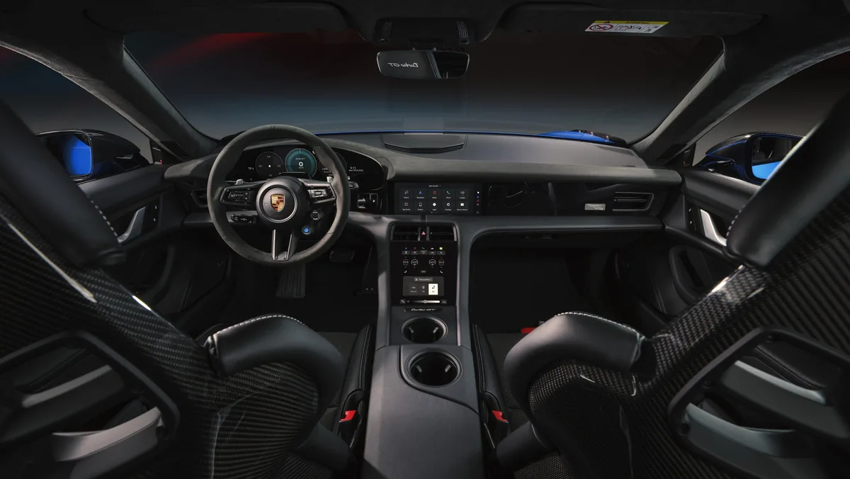 Interiér Taycanu Turbo GT ze zadní části vozu: dvě skořepinová sedadla s karbonovými zády, mezi nimi konzole se dvěma držáky nápojů, ve dveřích modré čalounění.