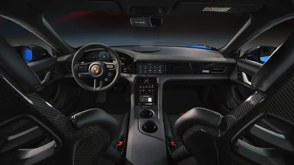 Interiér Taycanu Turbo GT ze zadní části vozu: dvě skořepinová sedadla s karbonovými zády, mezi nimi konzole se dvěma držáky nápojů, ve dveřích modré čalounění.